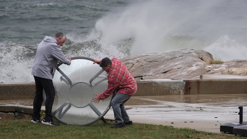 John Garrisi, left, and Gaige Graf move an outdoor table away from the shorefront during the...